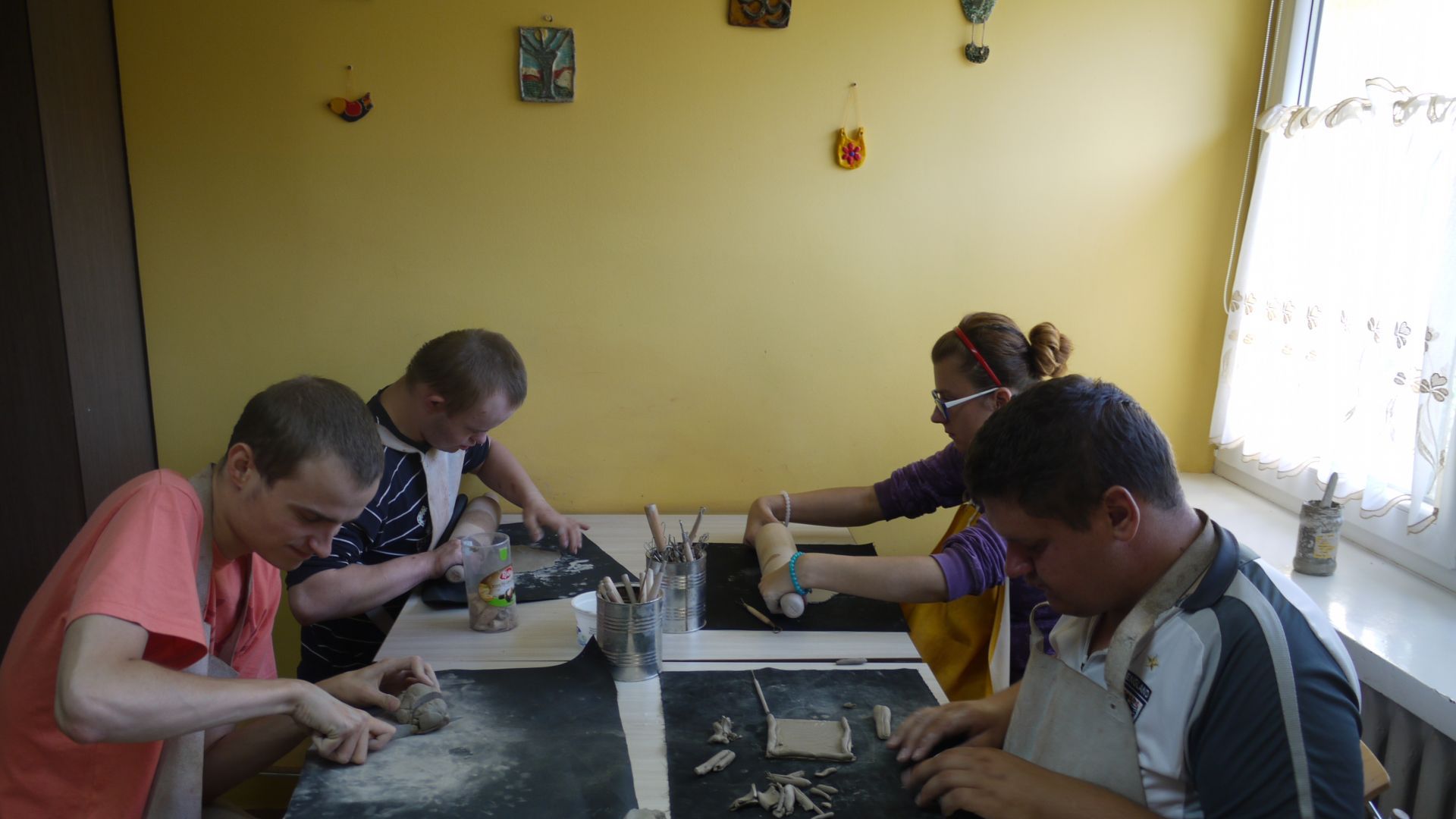 Uczestnicy wykonują prace z gliny w pracowni ceramicznej