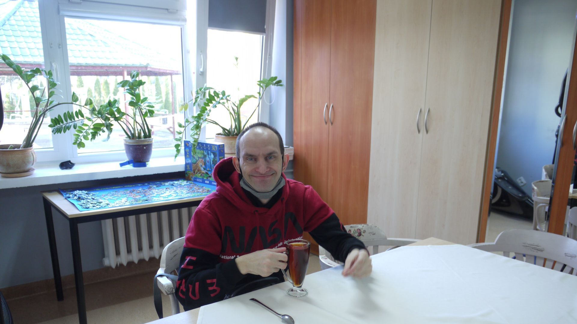 Paweł W. siedzący przy stole i pijący herbatę.