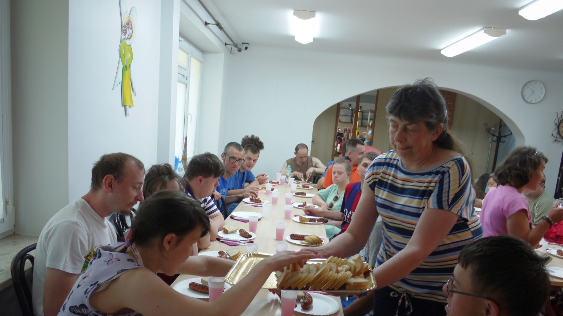 Uczestnicy częstujący się chlebem, który podaje pani Małgosia. 