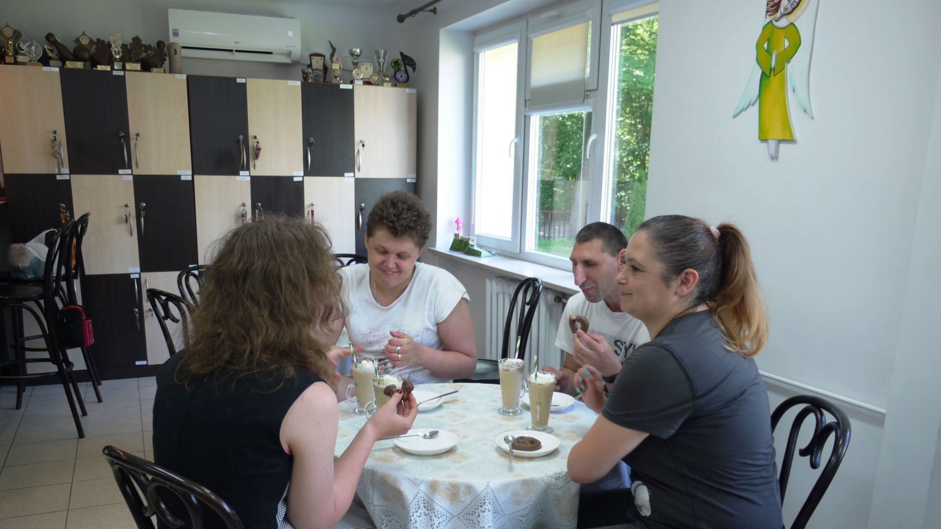Uczestnicy wraz z terapeutą podczas picia kawy przy stoliku w Art.-kawiarni.