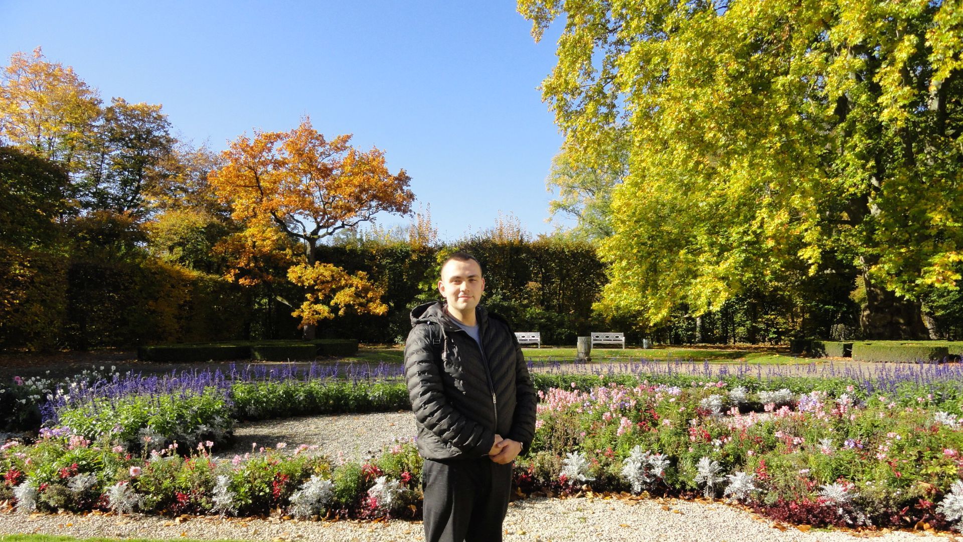 Uczestnik Paweł stojący na tle kwiatów w ogrodzie Radziwiłłów.