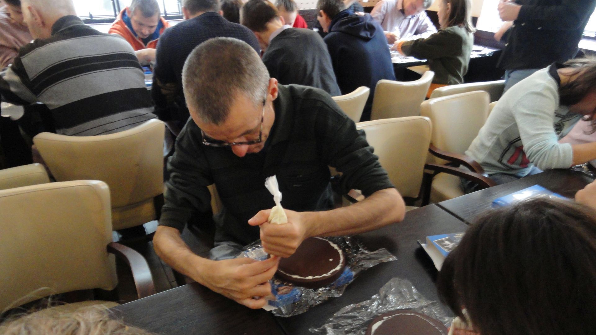 Grzegorz dekoruje torcik wedlowski biała czekoladą.