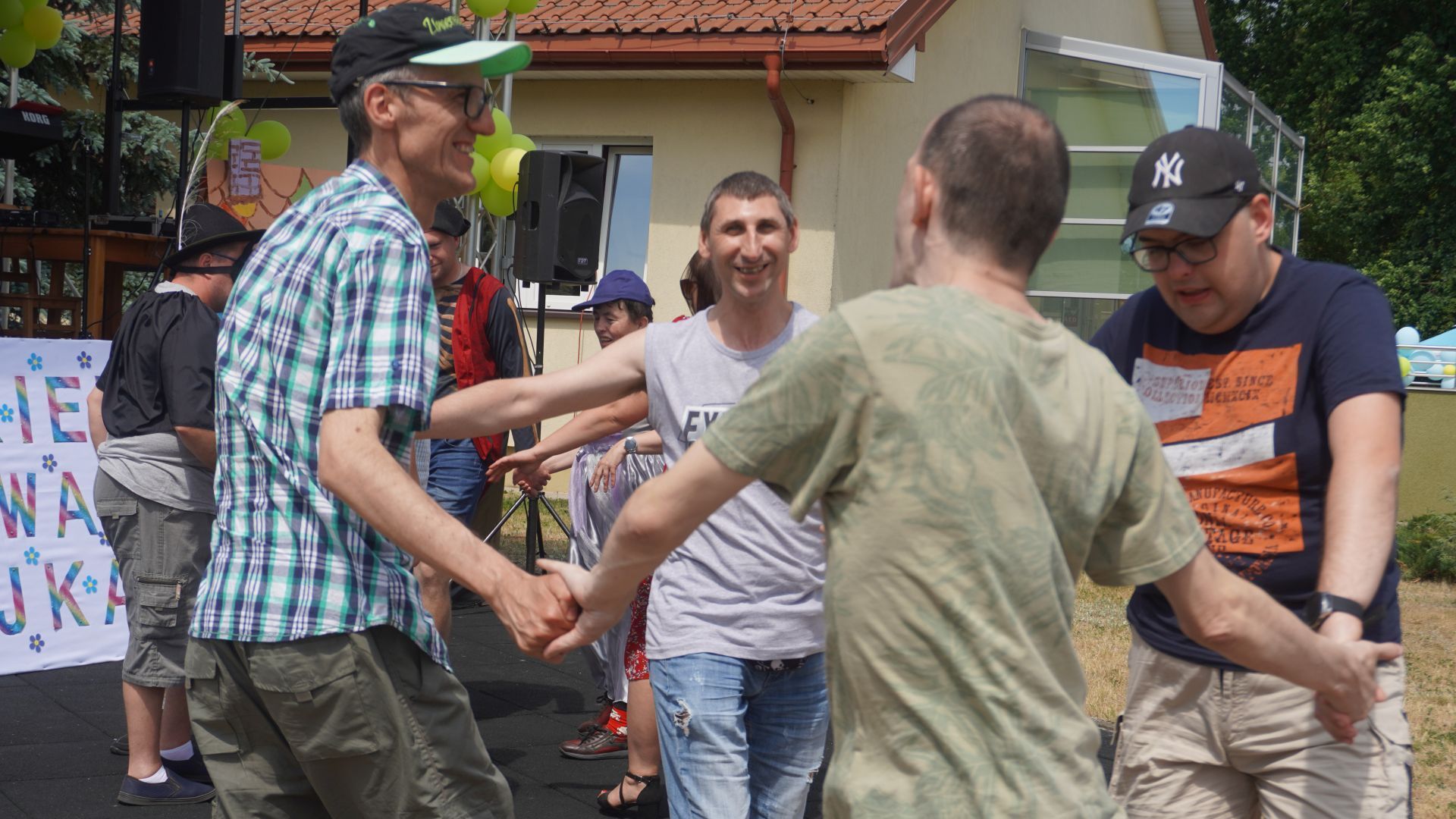 Uczestnicy tańczą w kole podczas Pikniku Rodzinnego ''Całkiem nowa bajka'' w DPS w Kątach.