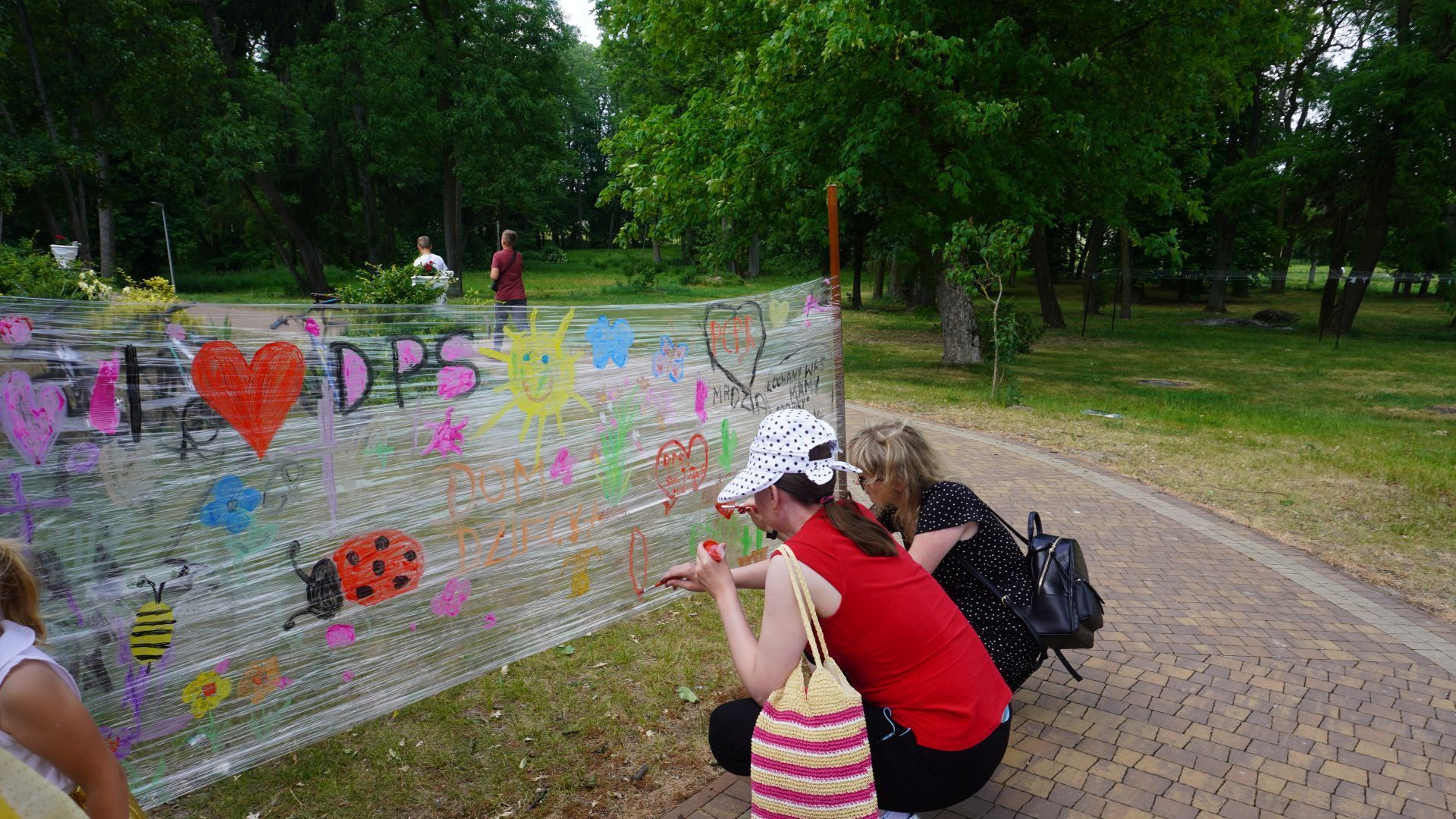 Uczestniczka Ania, wspólnie z terapeutą malują farbami po przezroczystej folii, na pamiątkę uczestnictwa w Pikniku Rodzinnym ''Całkiem nowa bajka'' w DPS w Kątach. 