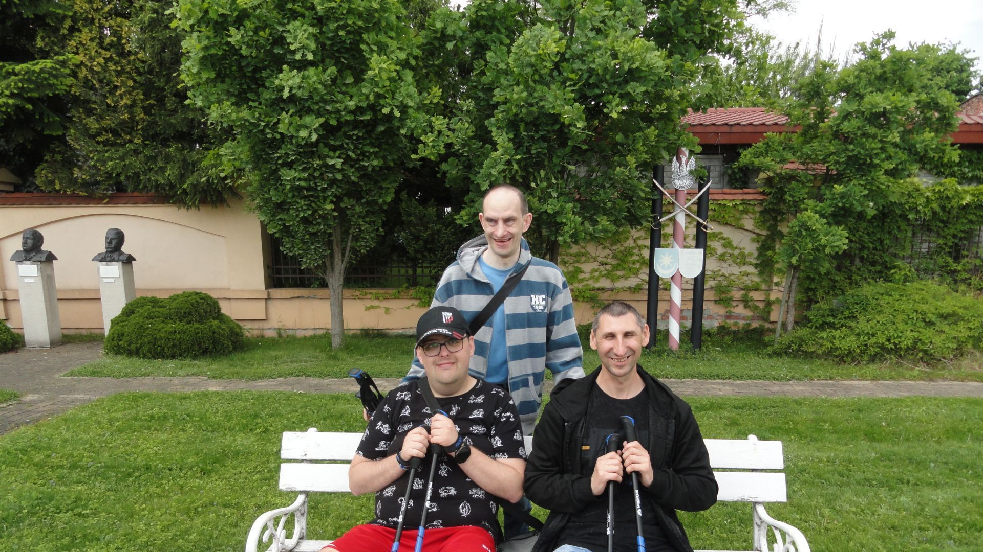 Uczestnicy odpoczywają na ławeczce podczas spaceru z kijkami do nordic walking.