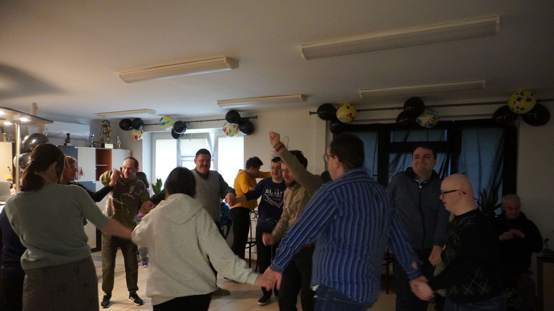 Uczestnik naszego Domu tańczą w kółku podczas imprezy andrzejkowej 2025.