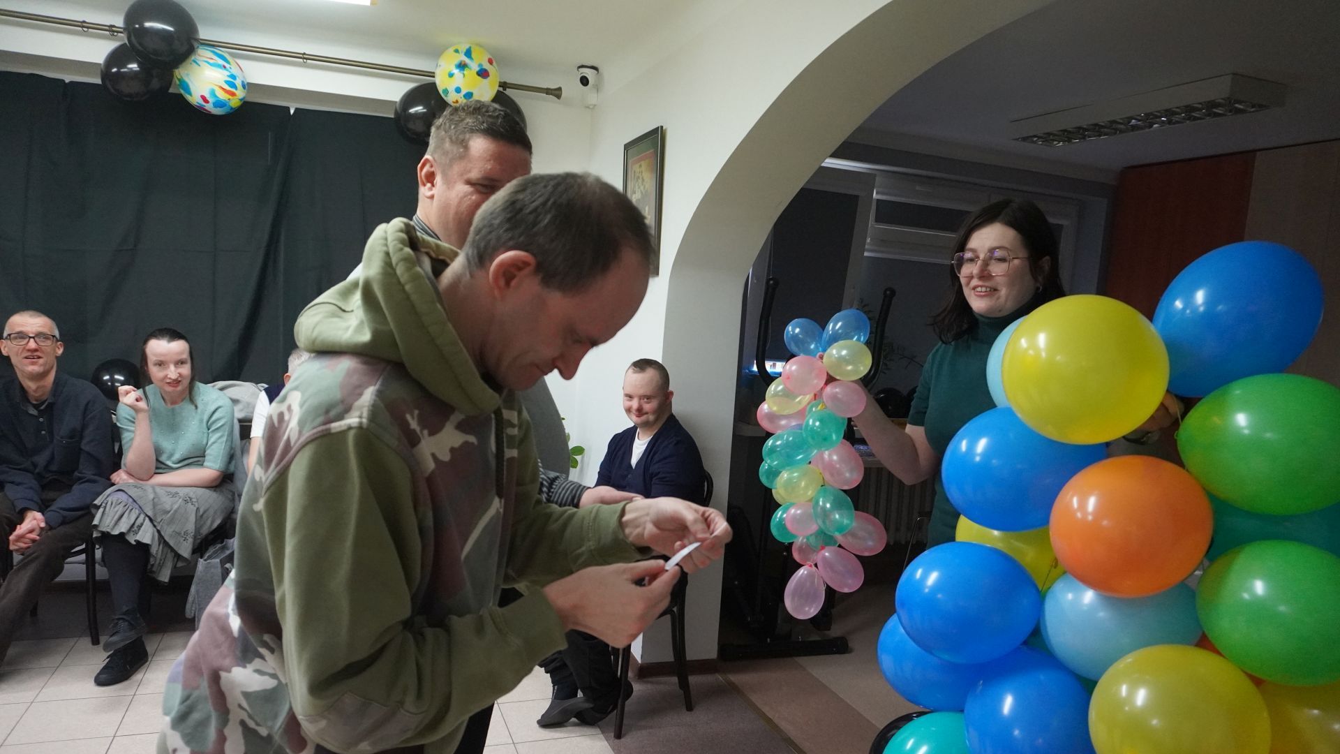 Uczestnik naszego Domu Paweł W. czyta karteczkę z wróżbą podczas imprezy andrzejkowej.