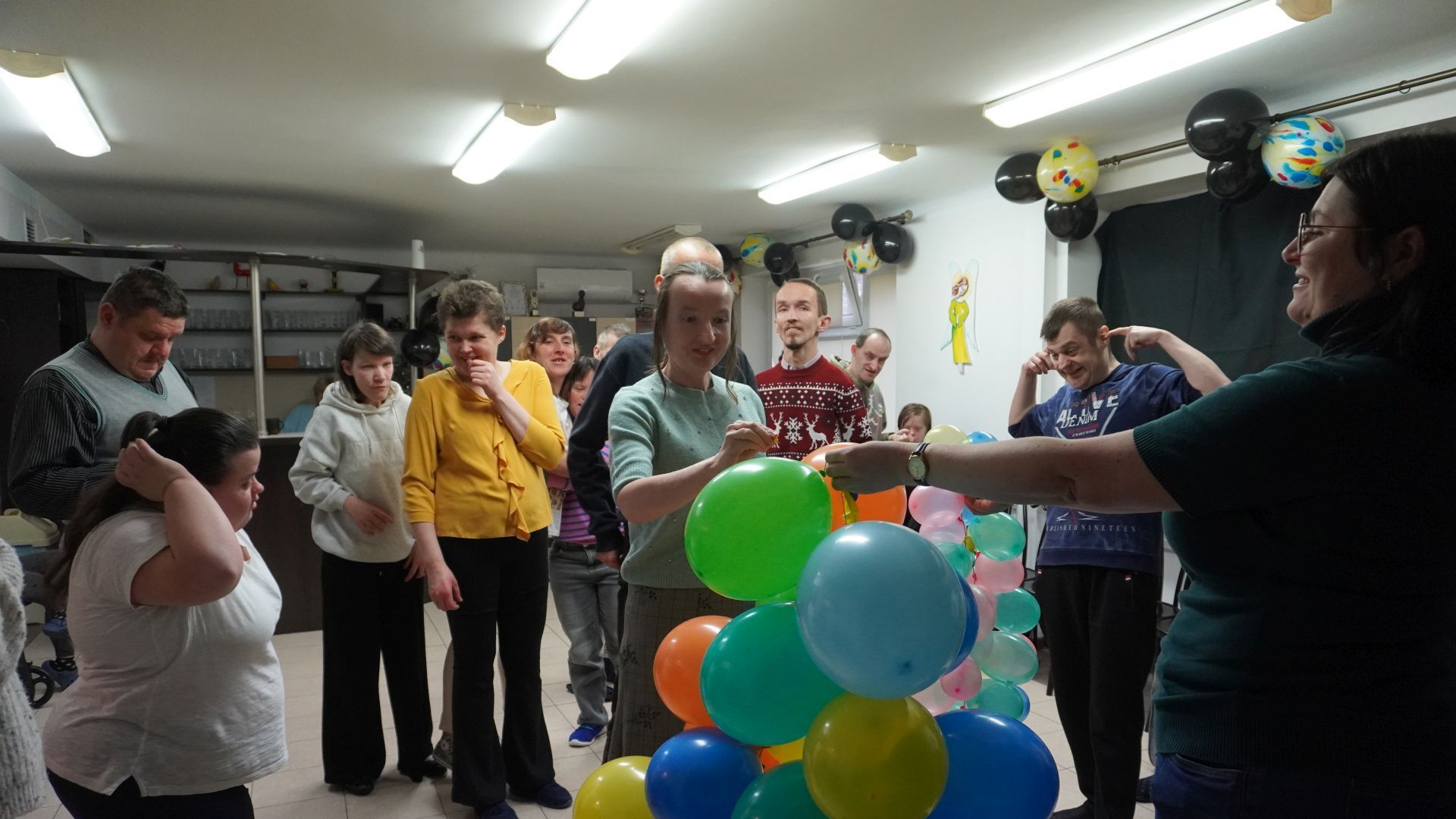 Uczestniczka naszego Domu Anna Cz. przebija balon z wróżbą podczas imprezy andrzejkowej 2025.