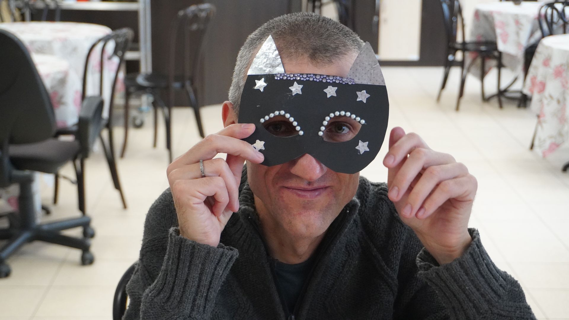 Uczestnik Grzegorz przymierza maskę karnawałową, którą sam wykonał.