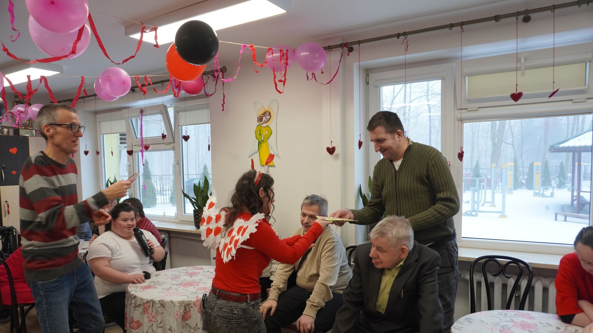 Przewodniczący Rady Domu wręczają kartki walentynkowe uczestnikowi Arkowi.