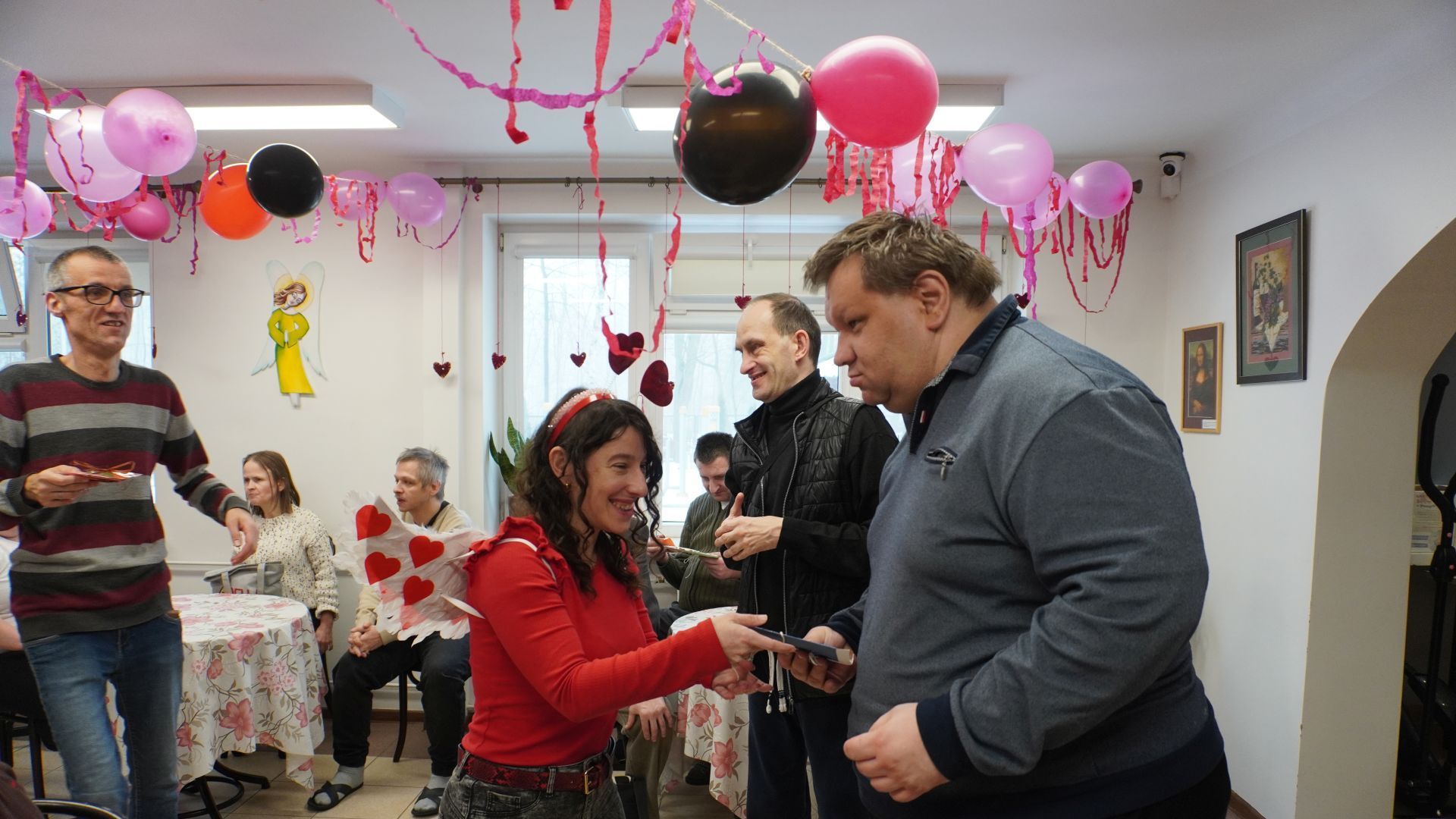 Przewodniczący Rady Domu wręczają kartki walentynkowe uczestnikowi Marcinowi.