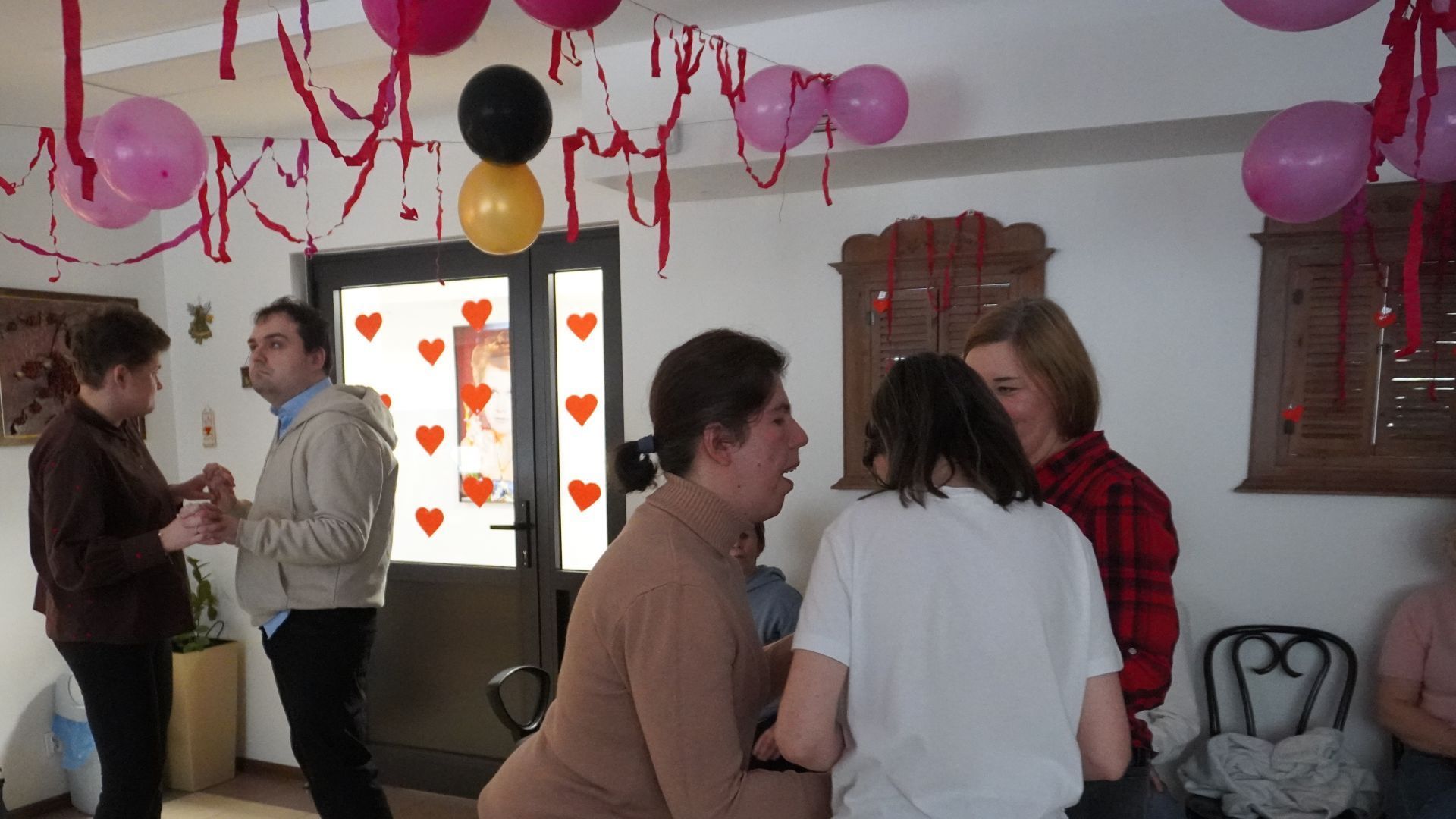 Uczestniczki PŚDS wraz z terapeutą tańczą w kółeczku podczas dyskoteki walentynkowej.