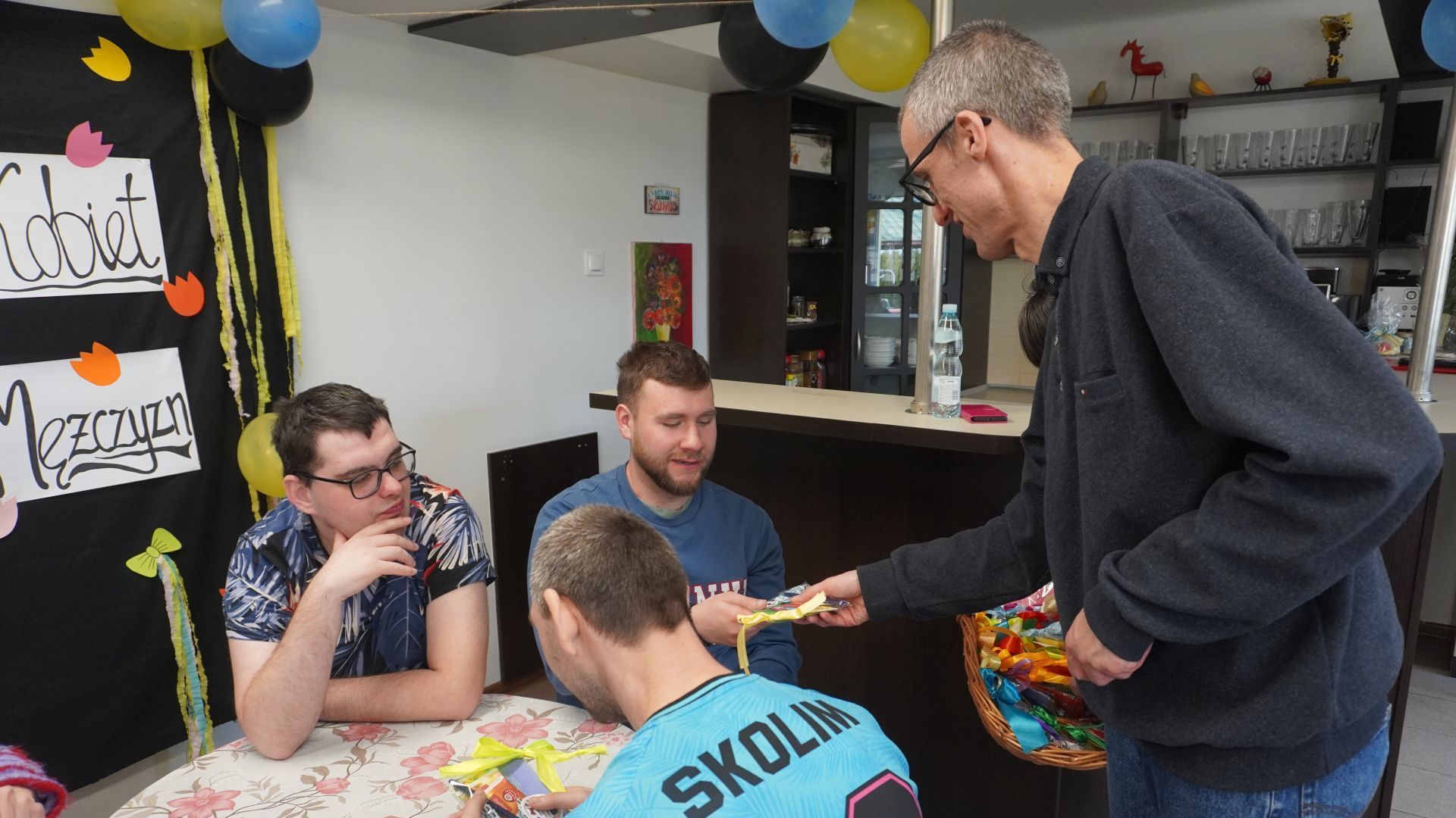 Uczestnik Grzegorz rozdaje upominki od Rady Domu z okazji Dnia Kobiet i Mężczyzn.