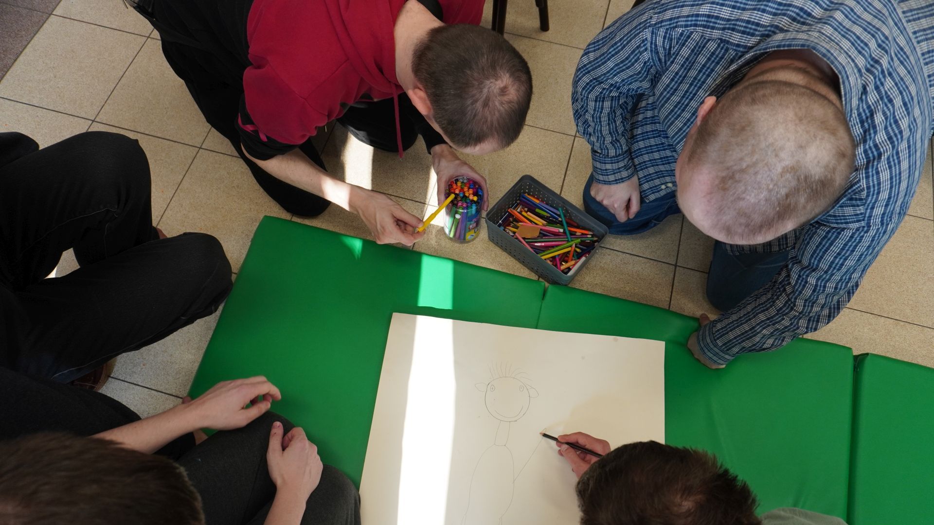 Uczestnicy PŚDS wykonują wspólną pracę plastyczną podczas zajęć integracyjnych z okazji Dnia Kobiet i Mężczyzn.