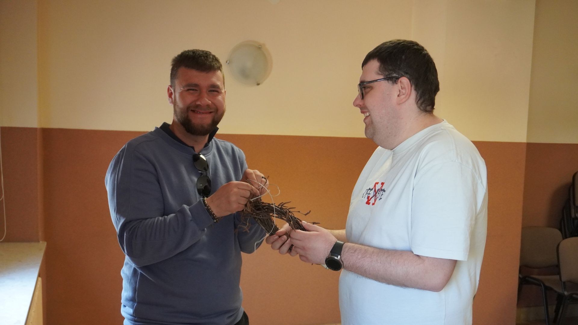 Uczestnicy Bartek i Karol wspólnie formują wianek z gałązek podczas wielkanocnych warsztatów artystycznych.