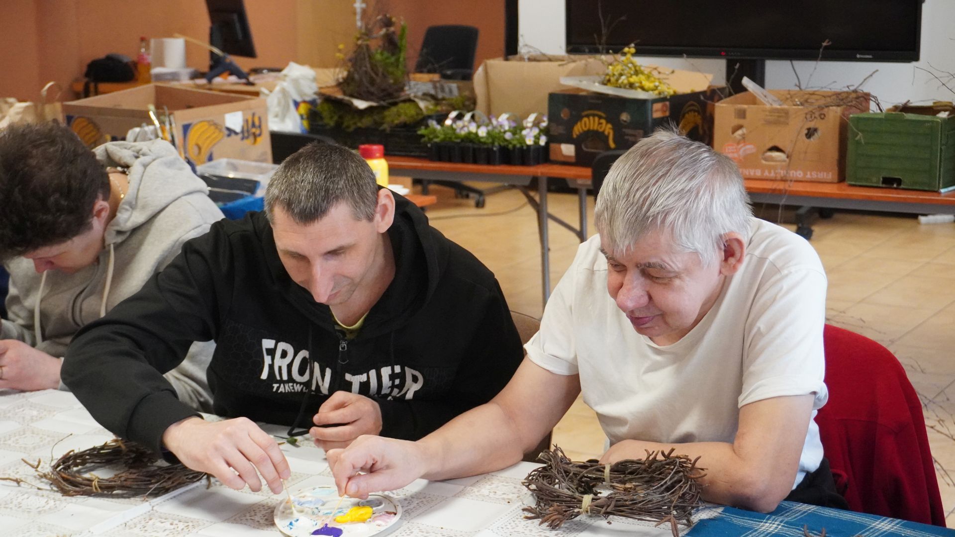 Uczestnicy Sebastian i Sławomir mieszają kolory farb podczas wielkanocnych warsztatów artystycznych.