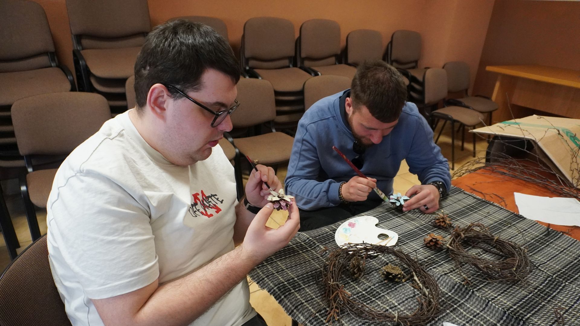 Uczestnicy Karol i Bartek malują szyszki podczas wielkanocnych warsztatów artystycznych.