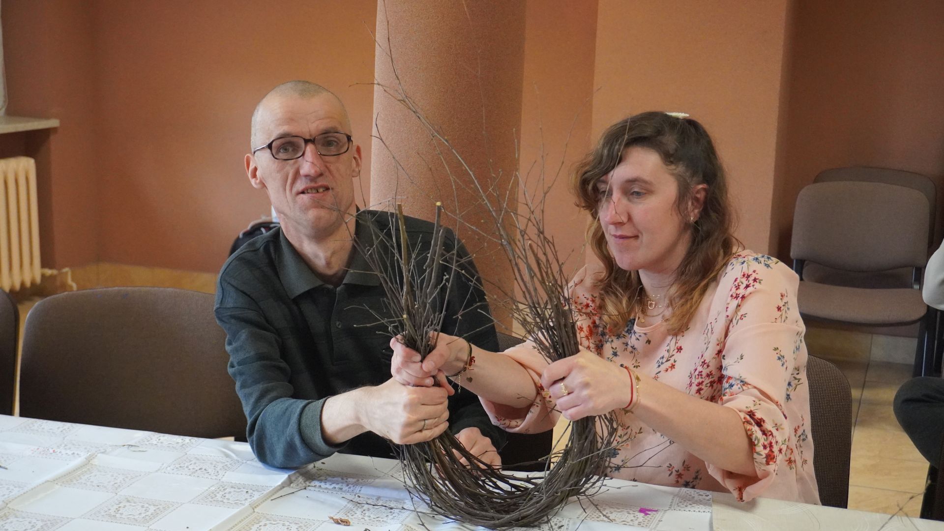 Uczestnicy, Grzegorz i Agnieszka podczas warsztatów wielkanocnych formują wspólnie koszyk z gałązek.