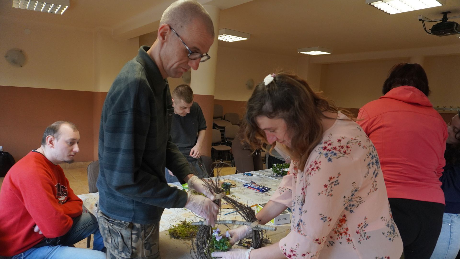 Uczestnicy, Agnieszka W. i Grzegorz robią wspólnie koszyk wielkanocny podczas warsztatów artystycznych.