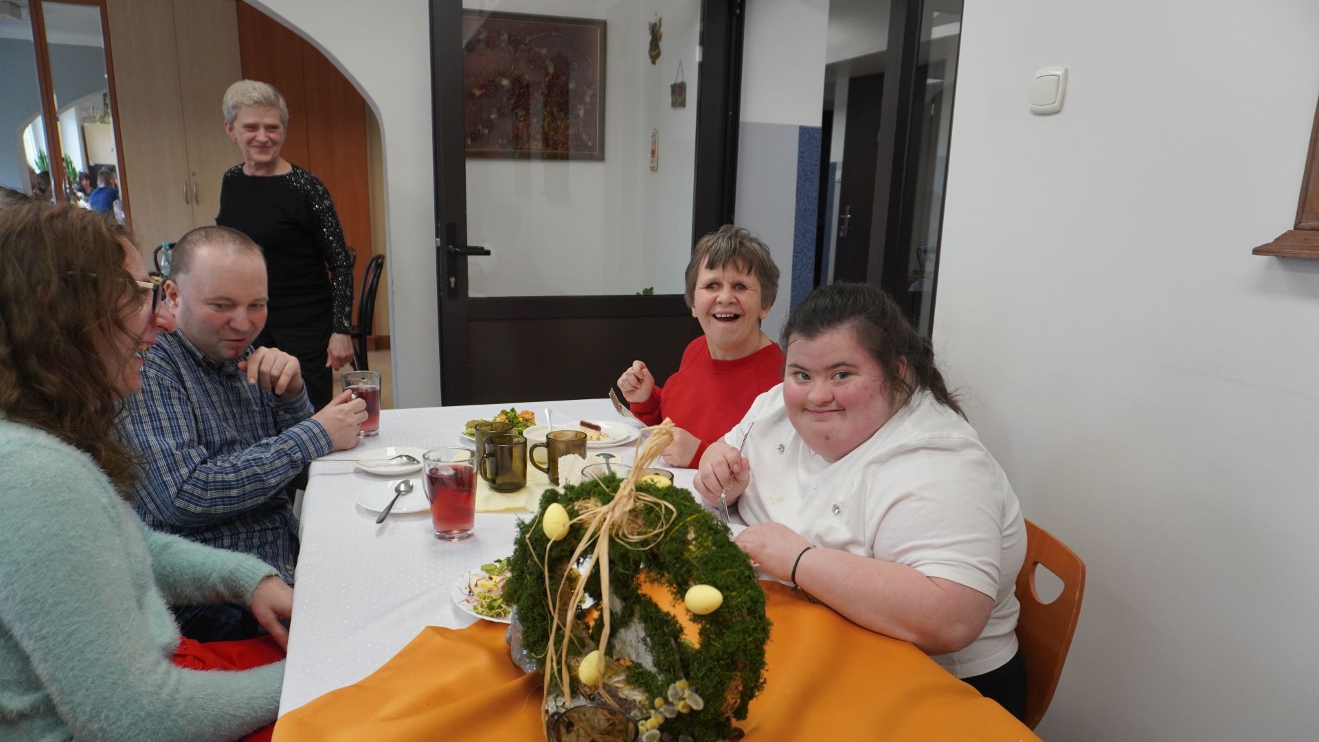 Uczestnicy siedzą przy stole podczas spotkania wielkanocnego.