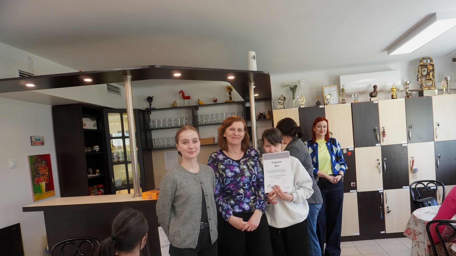 Uczestniczka Małgorzata odbiera dyplom i słodki upominek za zajęcie II miejsca w Turnieju Warcabowym 2026. 