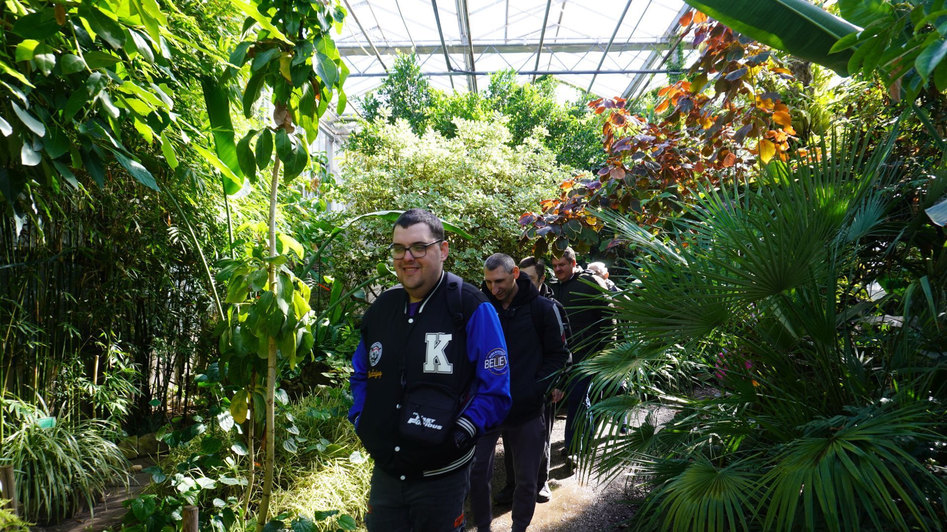 Uczestnicy słuchają pani przewodnik podczas zwiedzania oranżerii w Ogrodzie Botanicznym w Powsinie.