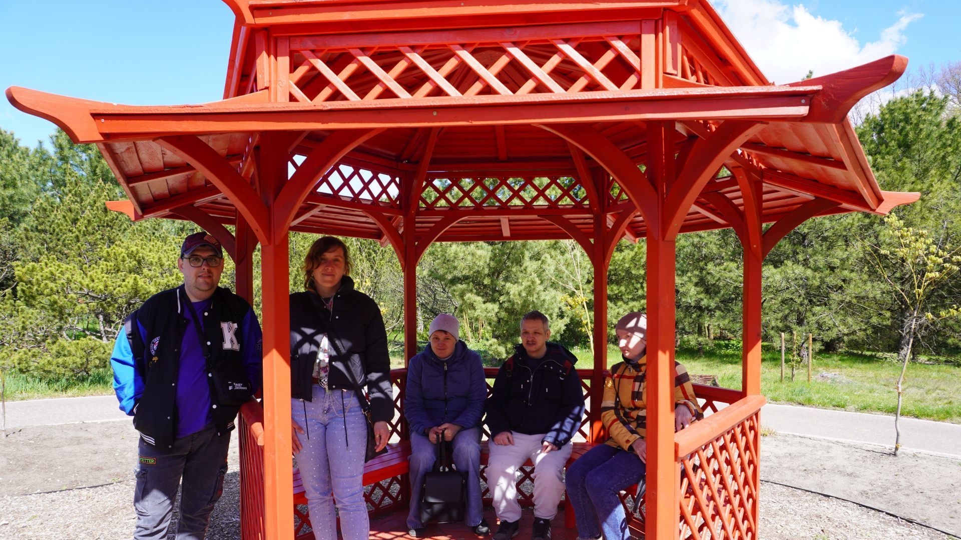 Uczestnicy pozują do zdjęcia w altanie podczas wycieczki do Ogrodu Botanicznego w Powsinie.