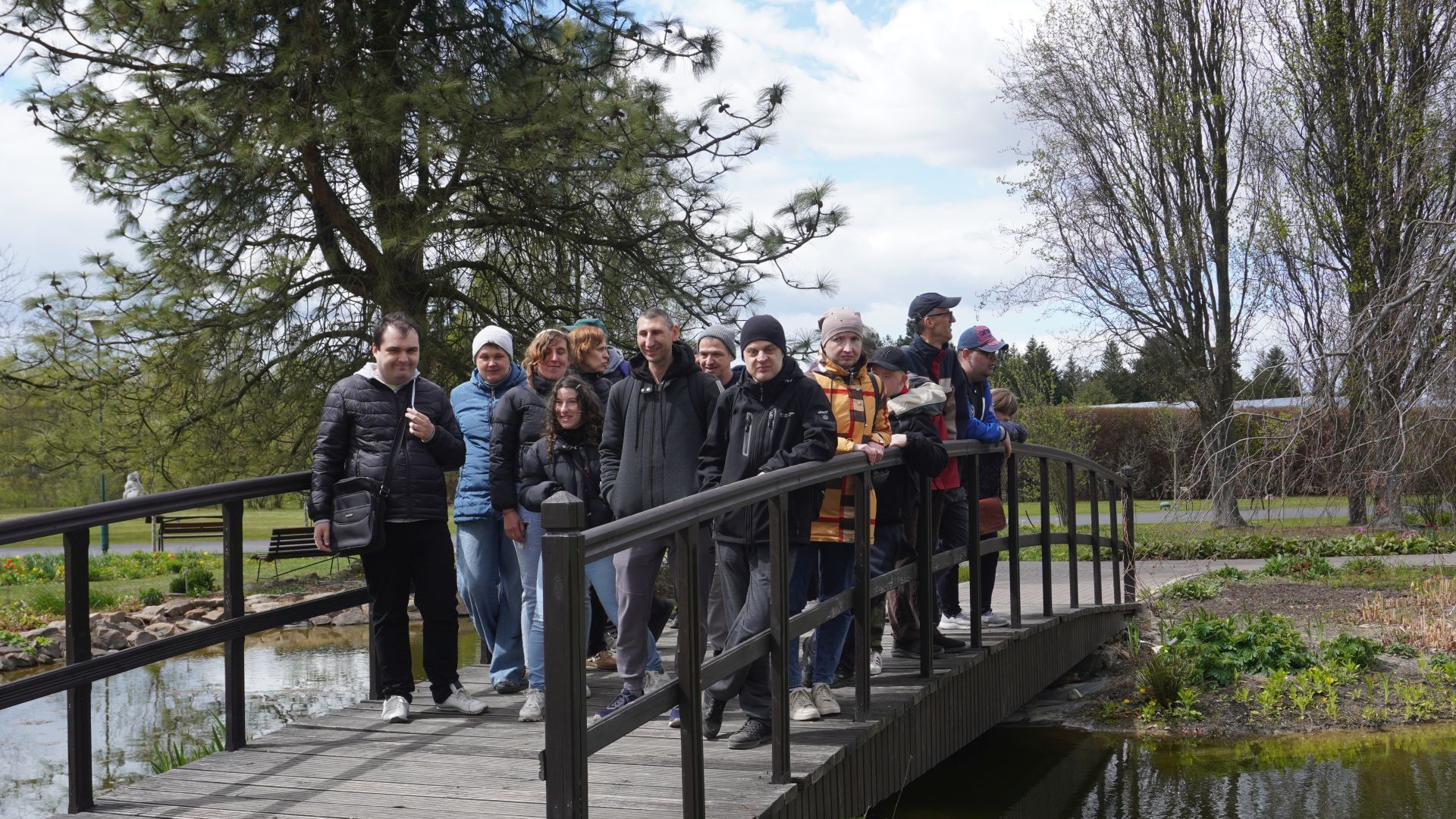 Uczestnicy wraz z opiekunami pozują do zdjęcia na mostku w Ogrodzie Botanicznym w Powsinie. 