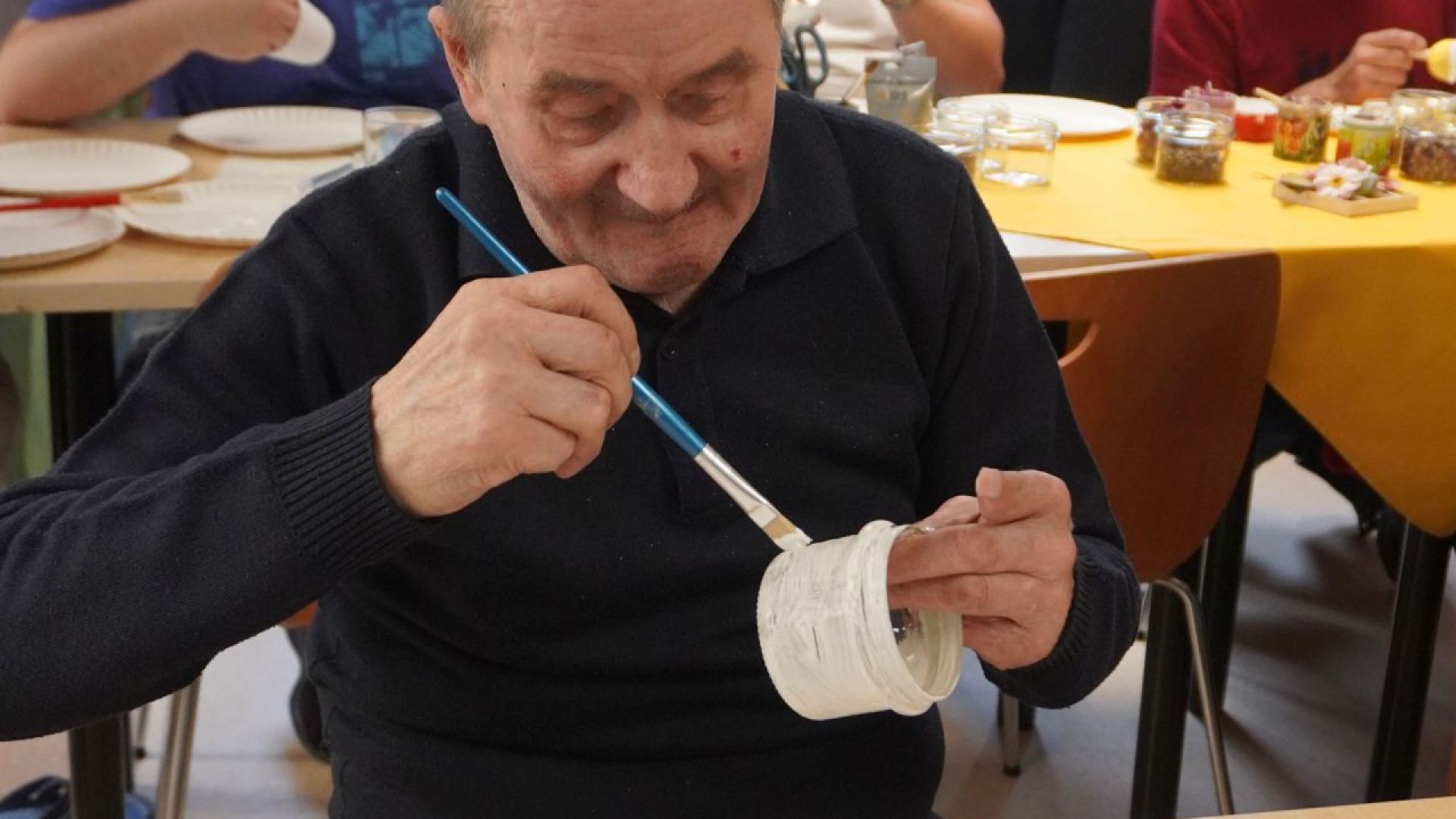Uczestnik warsztatów tworzenia świec w ramach projektu ''Jesteśmy da innych'' maluje szklany słoik.