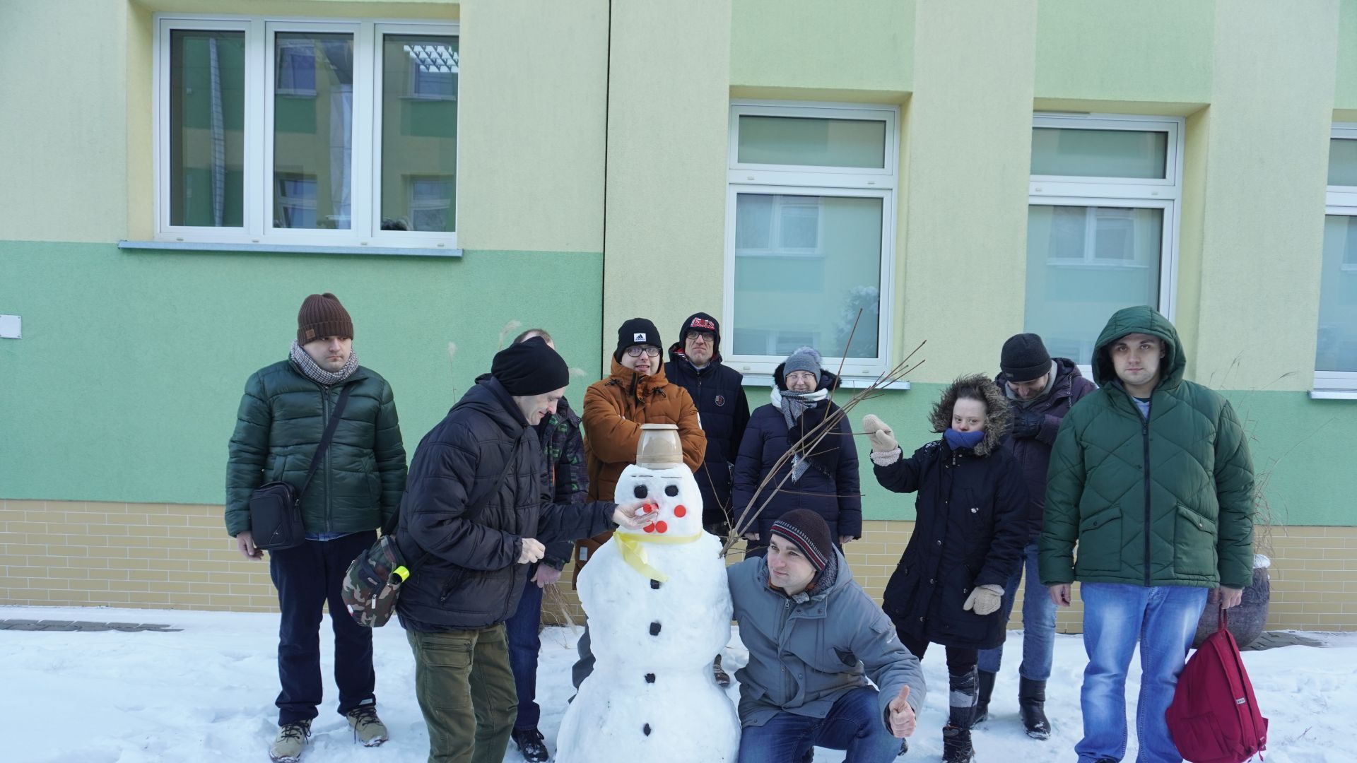 Uczestnicy pozują do zdjęcia ze śniegowym bałwanem.