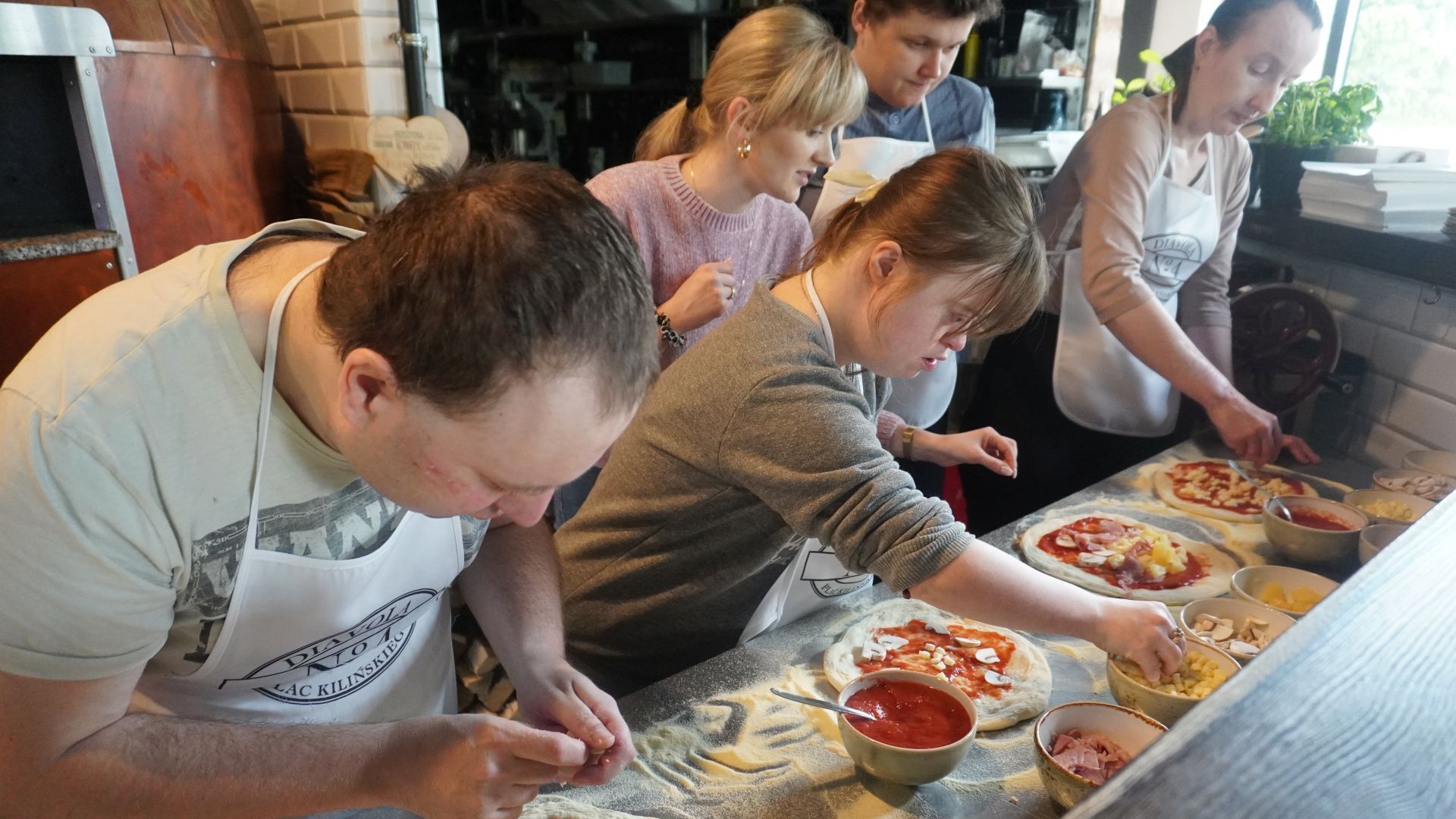Aktualności: Uczestnicy przygotowują swoje pizze podczas warsztatów w pizzerii Diavola. 